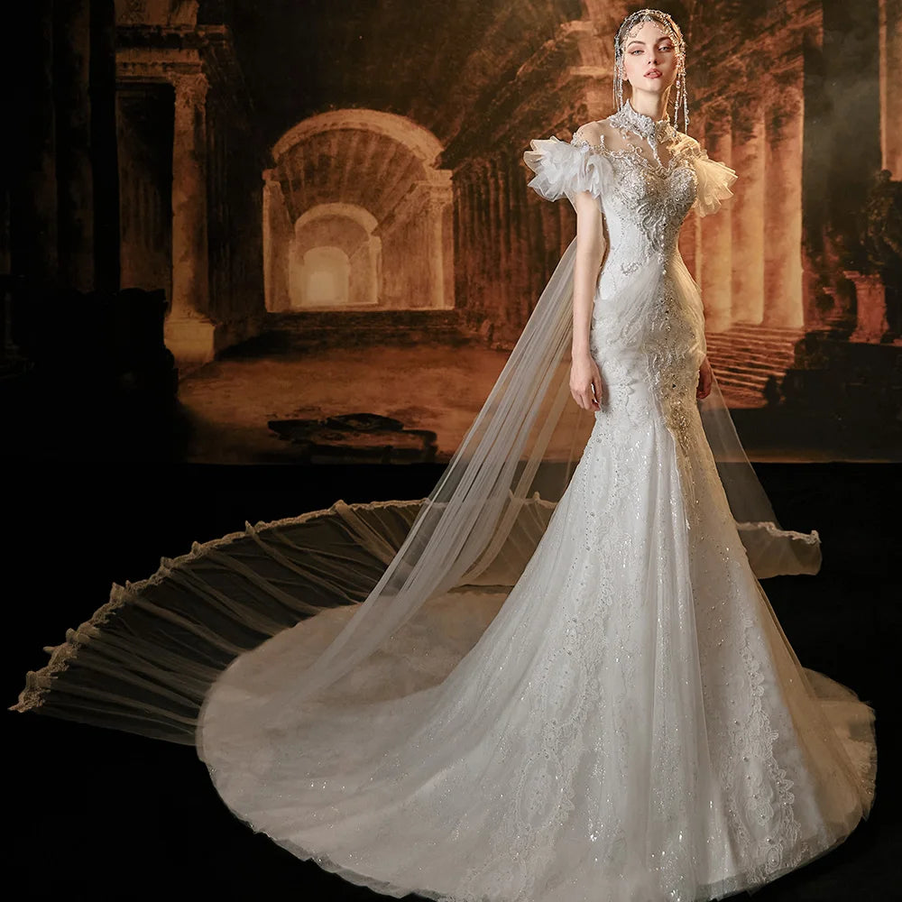 Elegant side perspective of a beaded lace mermaid wedding dress showcasing a fitted silhouette, elaborate crystal embroidery, and the flowing movement of the sheer Watteau train overlay.