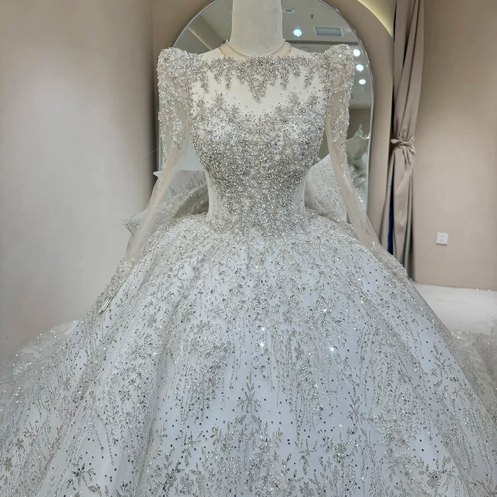 Detailed close-up of a bridal dress front bodice, showcasing high-density silver crystal beadwork, intricate branch-like sequin patterns, and a sheer embroidered neckline.