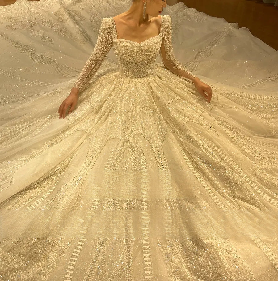 High-angle shot of a bride sitting to display the expansive, patterned shimmering skirt of a luxury fantasy-style wedding ball gown.