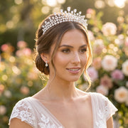 Close-up portrait of a smiling bride with an elegant low bun updo wearing a high-end marquise crystal bridal crown tiara and a matching lace wedding gown.