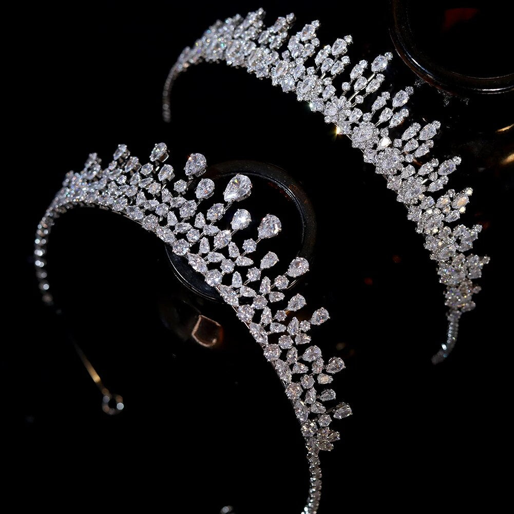 Flat lay overhead studio shot comparing two silver fascinator wedding bridal crowns heavily embellished with sparkling pear and marquise cubic zirconia gemstones.