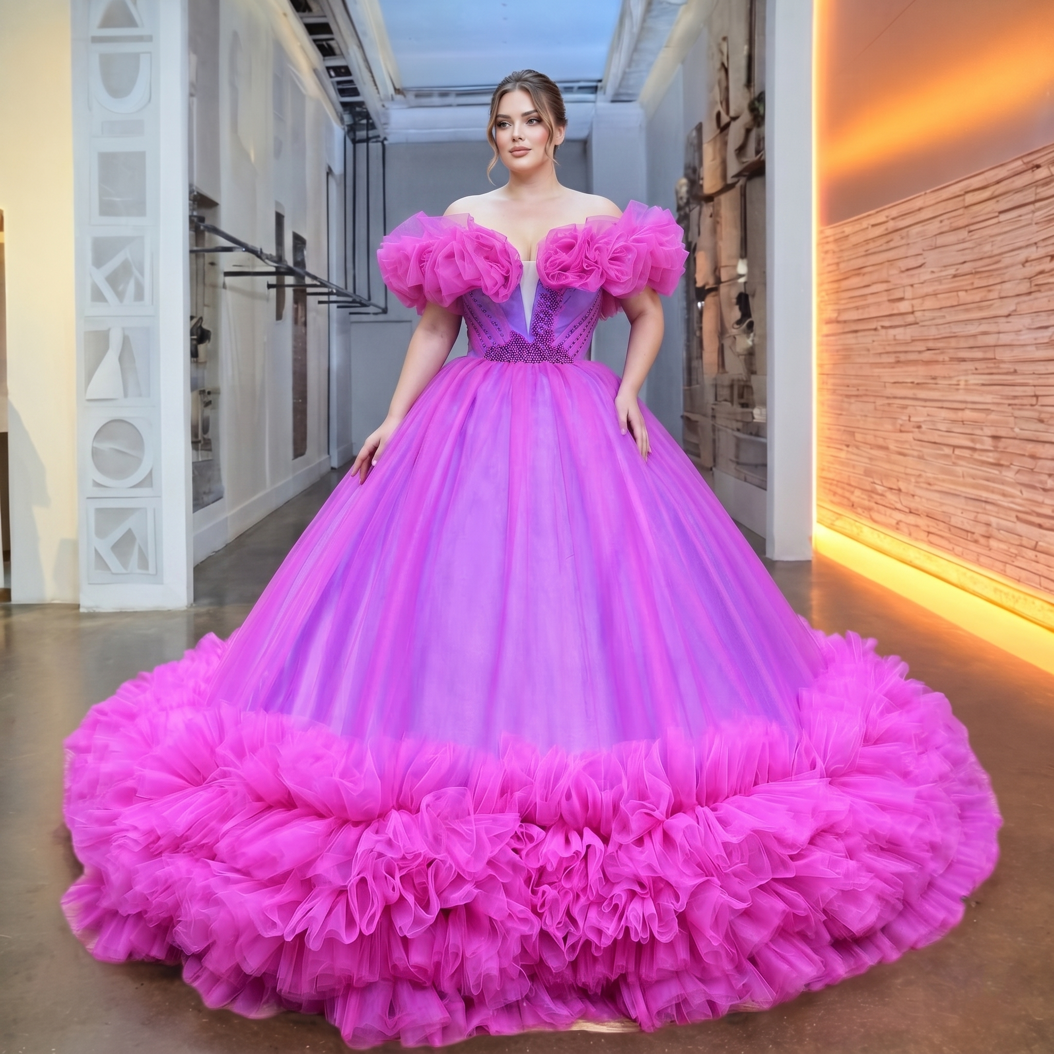 Plus size model showcasing a dramatic magenta pink tulle wedding dress with oversized ruffled off-the-shoulder sleeves and a heavily beaded bodice in a modern showroom.