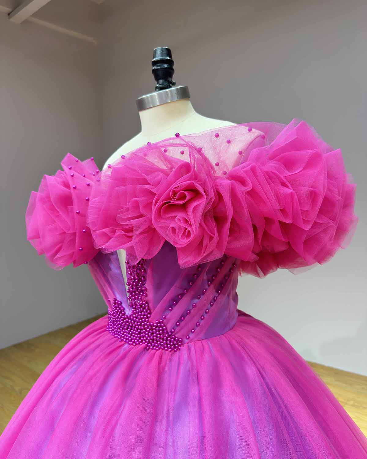 Detailed side profile view of the structured bodice, diagonal pearl boning details, and oversized ruffled tulle sleeves on a vibrant pink wedding dress.