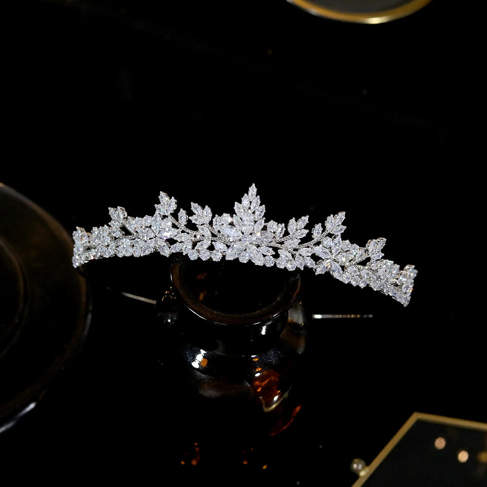 Front profile view of a high-quality silver rhinestone wedding crown hair band placed on a black reflective surface.