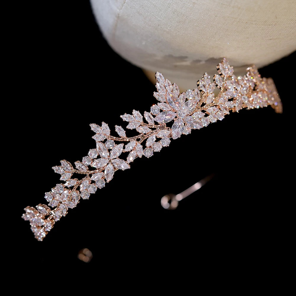 Perspective close-up view of an elegant rose gold crystal floral leaf crown tiara resting on a white display head.