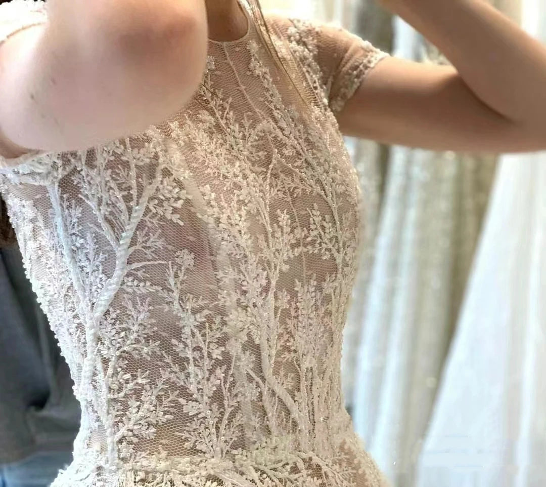 A bride wearing a floor-length vintage bohemian wedding dress with delicate lace appliqués and short sleeves.