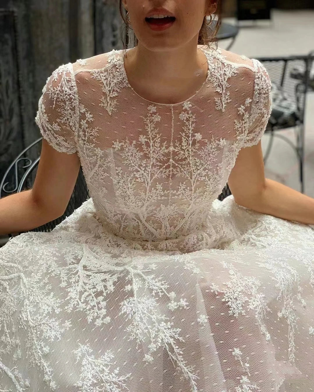 Close-up of the intricate lace appliqué detailing on the bodice and short sleeves of a vintage-style bohemian wedding gown.