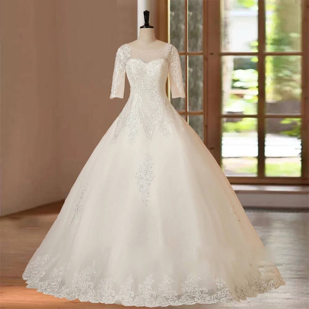 Mannequin displaying a white floor-length bridal ball gown with half sleeves and delicate lace applique details.
