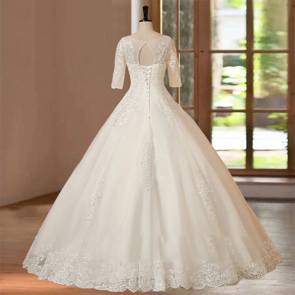 Back view of a floor-length wedding gown on a mannequin, showcasing the sheer illusion back, lace embroidery, and half sleeves.