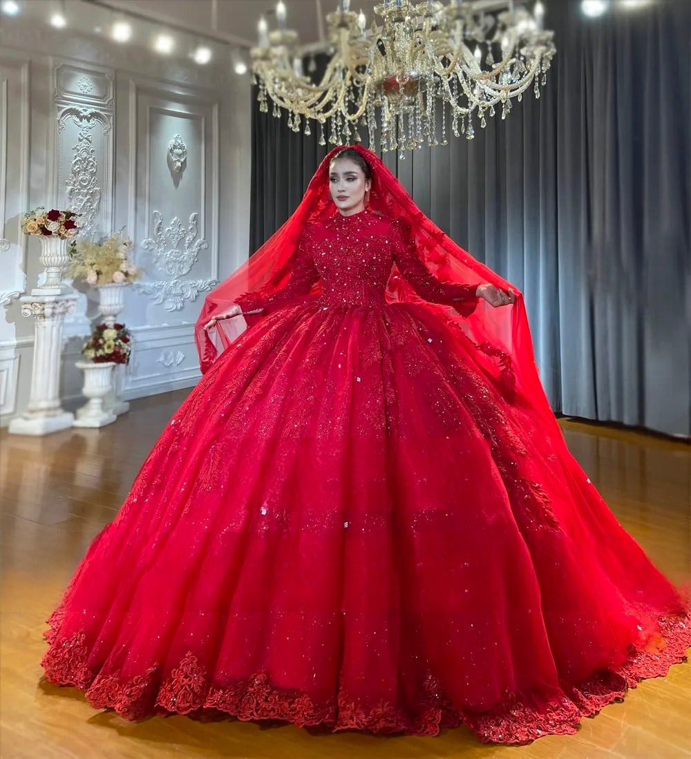A beautiful bride posing in a full coverage wine red Muslim wedding dress, complete with a matching long red bridal veil flowing over the sparkling ball gown skirt.