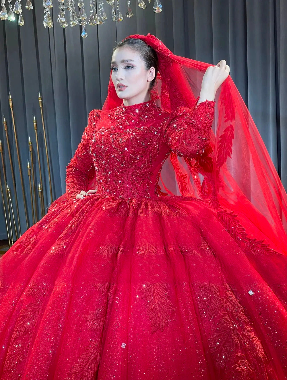 Close-up detail of a bride in the elegant modest bridal gown, showcasing the matching wine red veil, intricate heavy beadwork on the high neckline, and delicate long sleeves.