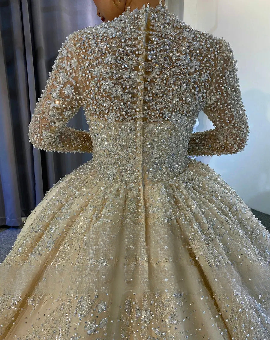 Detailed back view of the upper bodice of a luxury wedding dress featuring a high-neck design and sheer long sleeves covered in dense pearl and crystal patterns.