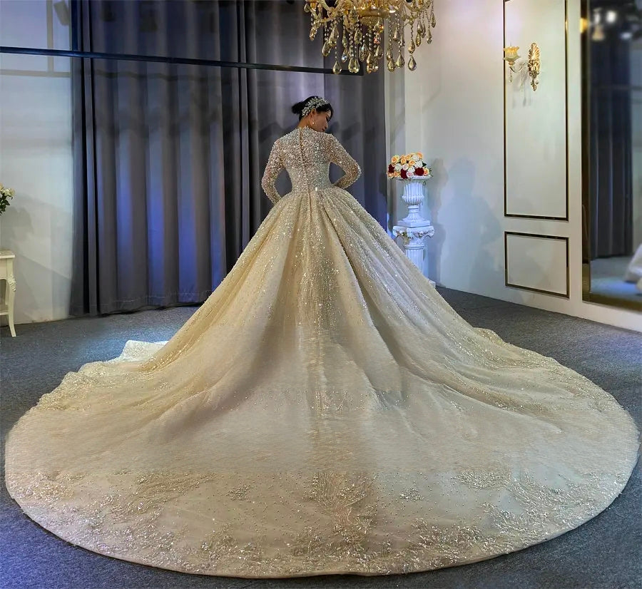 Stunning back profile of a luxury bridal ball gown with a majestic, wide-reaching long train adorned with heavy pearl embellishments and sparkling crystals.