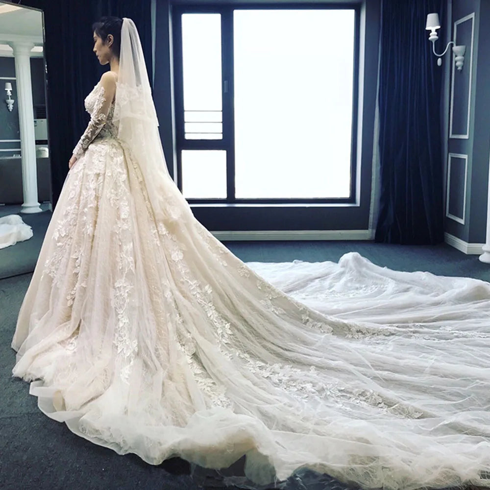 Side profile view of a stunning A-line bridal gown featuring full lace sleeves and a dramatic, elegant long train.