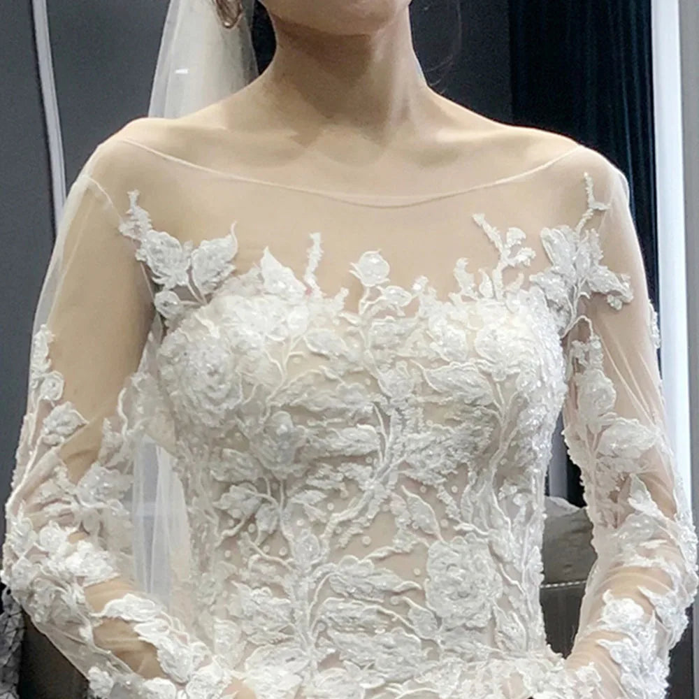 Detailed close-up of the delicate beaded appliques and sheer illusion neckline on a full sleeve bridal gown.