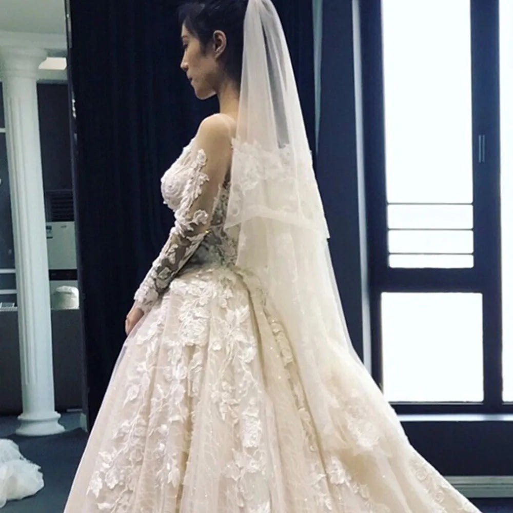 Elegant side-view of a full sleeve lace bridal gown with a long train, captured in an indoor setting.