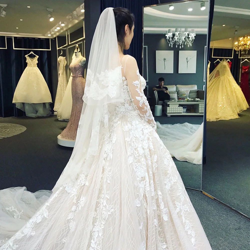Full-length view of a long-sleeve A-line bridal gown with a dramatic long train on a mannequin.