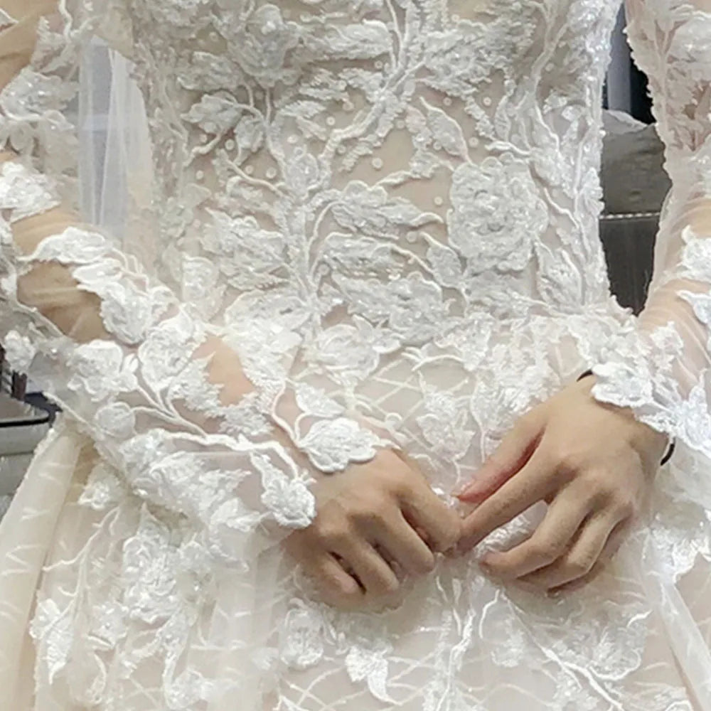 Detailed close-up of a mannequin wearing an A-line wedding dress, highlighting the beaded lace appliques on the long sleeves.