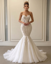 Front view of a model wearing a glamorous strapless mermaid wedding dress with an intricate beaded bodice and a flared tulle skirt.