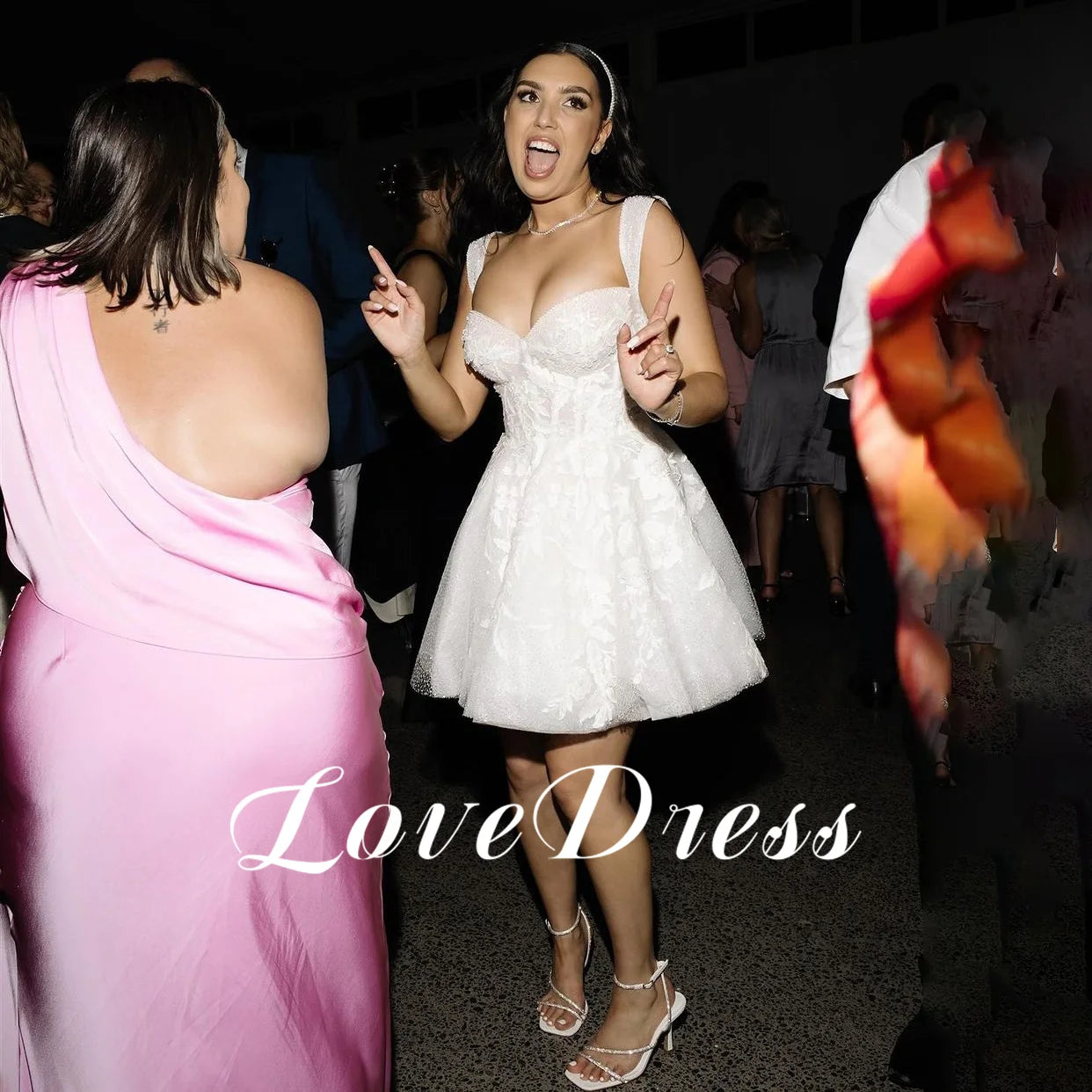 Sparkling short white bridal gown with thick lace straps and an intricately embroidered sequin bodice, styled as a fun second-look reception dress for dancing.