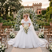 Bride posing outdoors in a luxury glitter short-sleeve ball gown wedding dress with a sweetheart neckline and elegant tassel back detail.