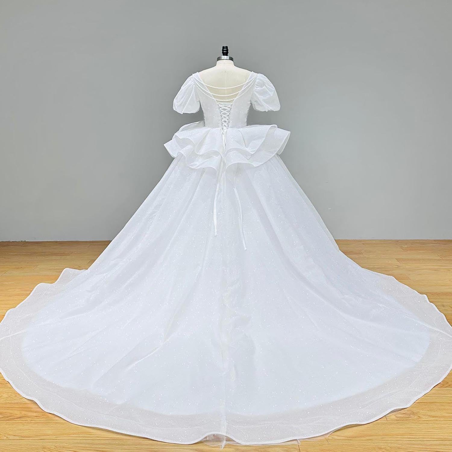 Back profile of a glitter short-sleeve ball gown wedding dress with a sweetheart neckline on a display mannequin.