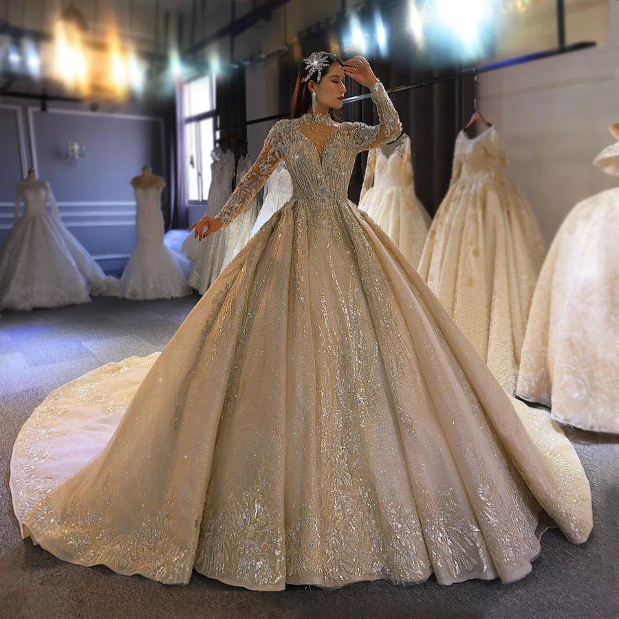 Full front-side view of a high-quality gold ball gown wedding dress with long sleeves and a high neck, featuring a majestic shimmering cathedral train in a bridal studio.