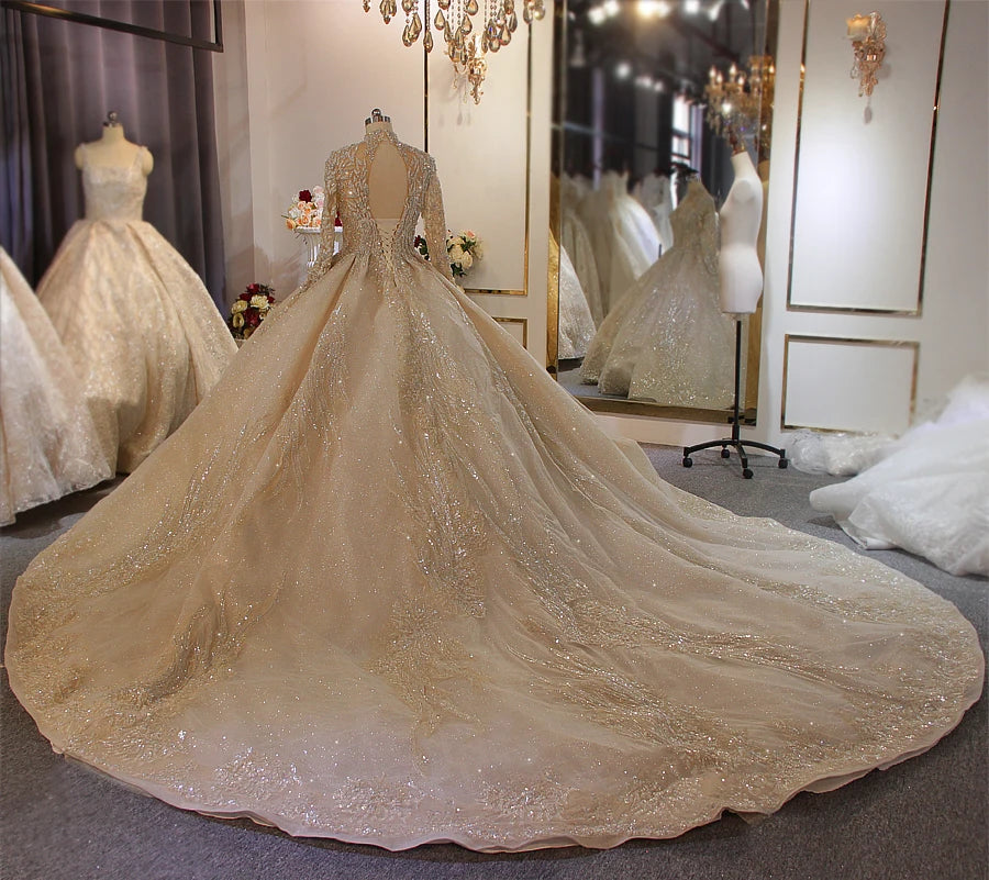 Rear view of a luxury gold wedding dress on a mannequin, highlighting the intricate silver beadwork and an expansive, sparkling circular cathedral train.