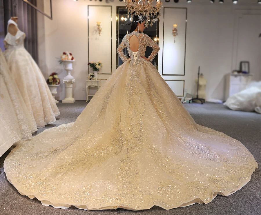 Real work back view of a luxury gold wedding gown on a bride, featuring a keyhole back opening and an adjustable lace-up corset with a massive train.