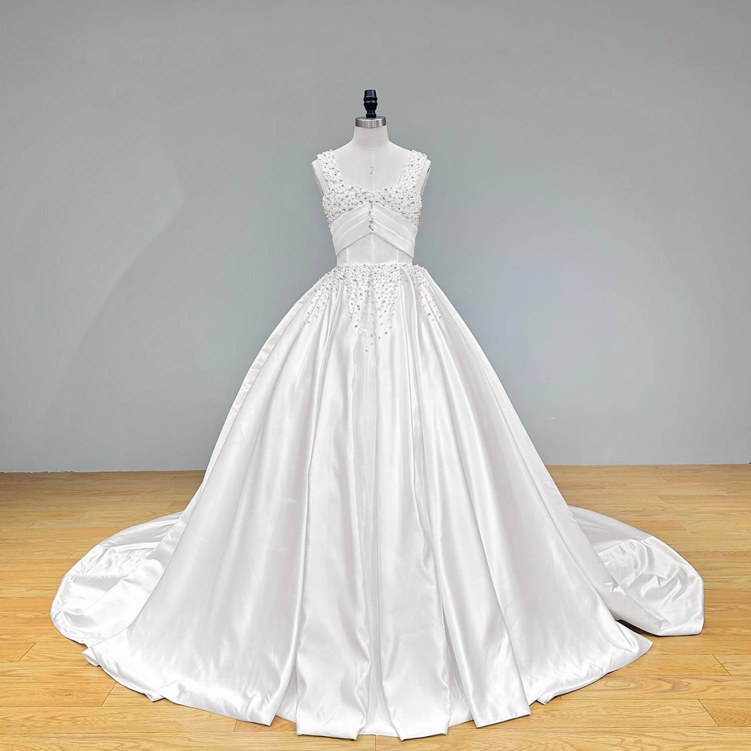Full front perspective of the heavy tailored white satin wedding dress on a dress form against a solid gray studio background, highlighting its premium silk texture.