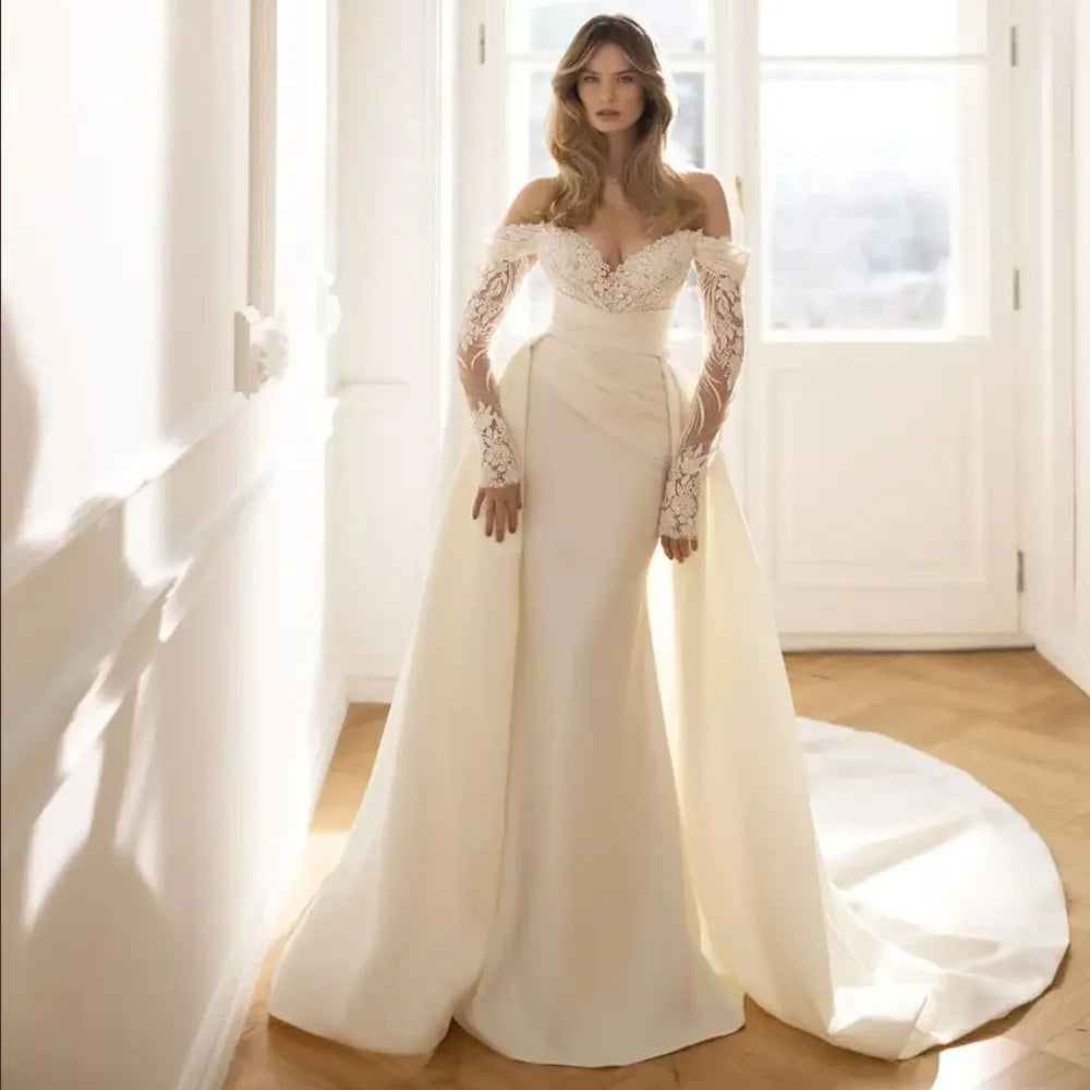A mannequin displaying a gorgeous long-sleeve mermaid wedding dress with intricate lace embroidery and a dramatic detachable train.