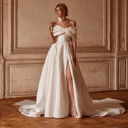 Elegant off-the-shoulder satin wedding dress with a structured criss-cross portrait collar, clean pleated bodice, high thigh-slit skirt, and sweeping chapel train.
