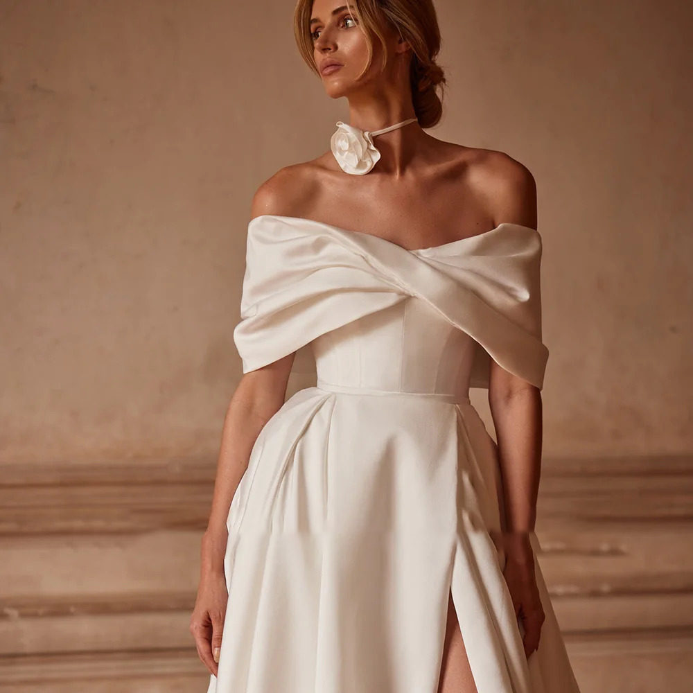 Close-up of a structured silk-satin wedding dress bodice showcasing a dramatic overlapping off-the-shoulder portrait cuff neckline.