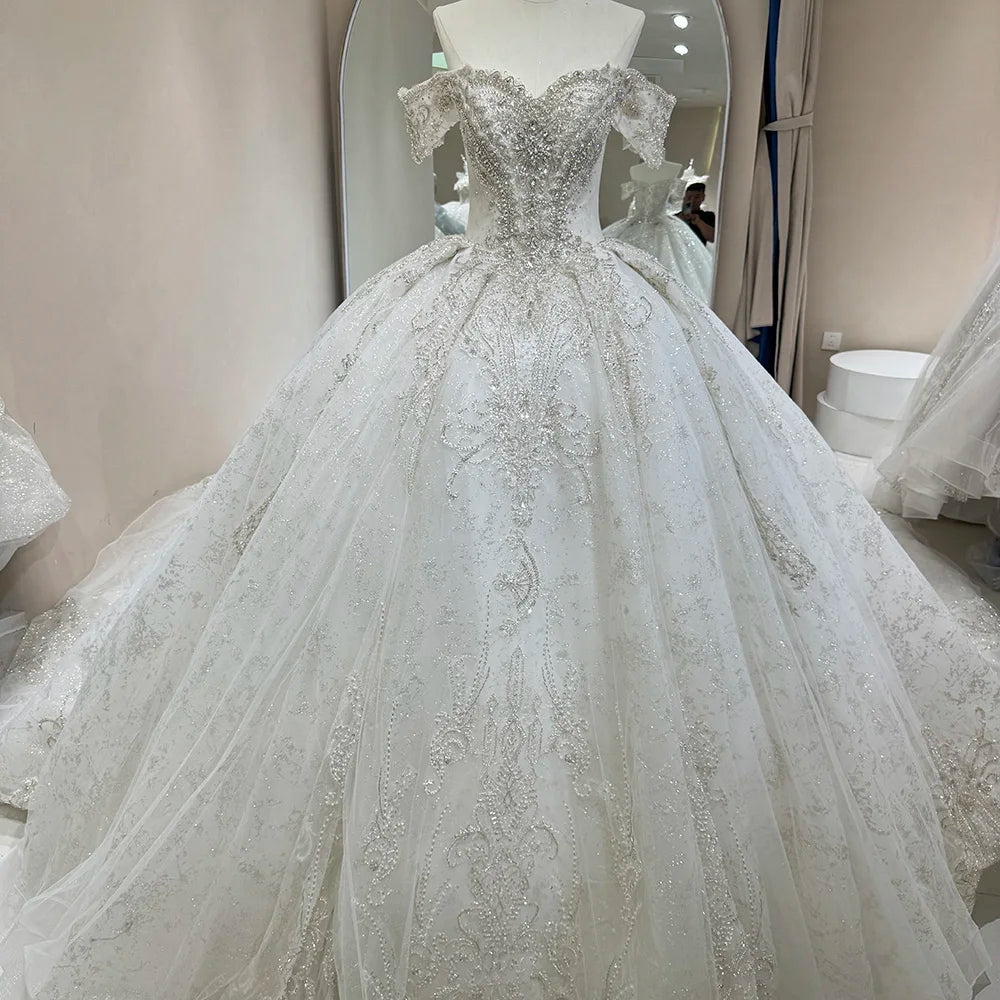 Professional mannequin display of a white off-shoulder sleeveless bridal dress with intricate hand-beaded silver crystals and a royal princess silhouette.