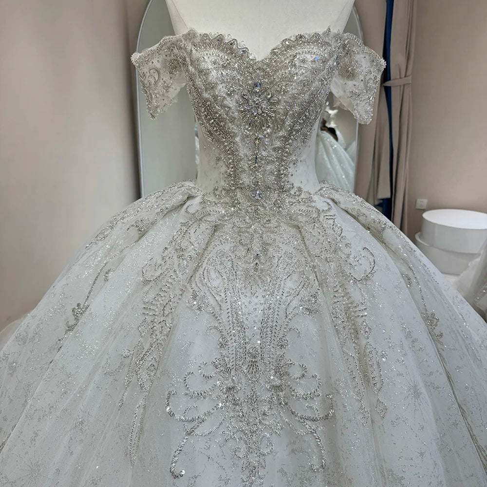 Back view of a beaded white bridal gown on a mannequin, showcasing an elegant lace-up corset back and a wide-sweep shimmering elegant train.