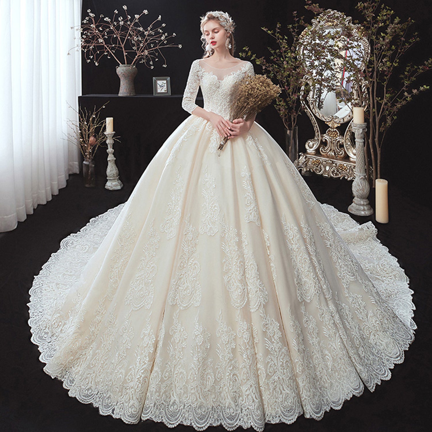 Elegant blonde bride holding dried florals in a luxury champagne-toned ball gown wedding dress with an illusion scoop neckline and 3/4 sleeves.