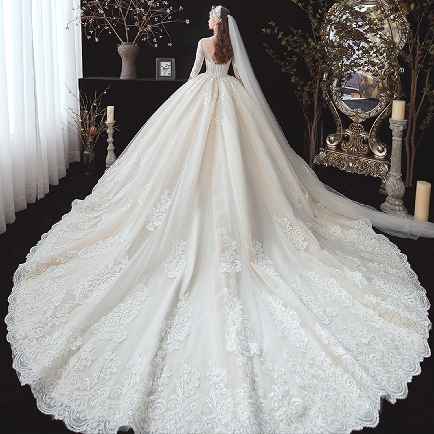 Full rear view of a bride displaying an expansive cathedral-length tulle wedding dress train adorned with dense scalloped lace embroidery.