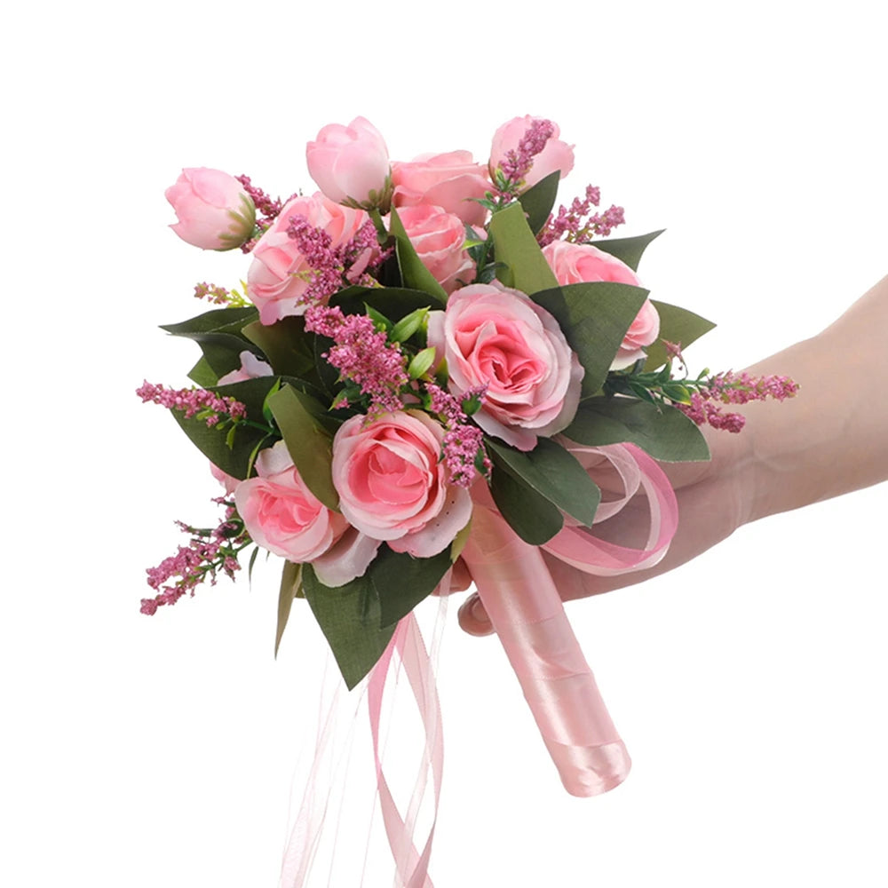 Close-up of a hand holding an artificial pink and white silk rose bridal bouquet for wedding decor against a white background.