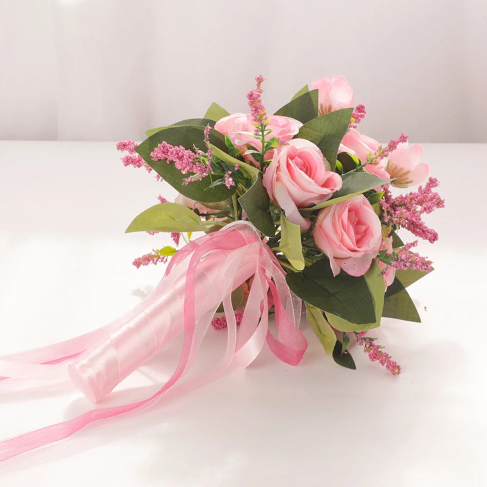 High-angle studio view of a handmade pink silk rose bridesmaid bouquet resting gracefully on a white reflective surface.