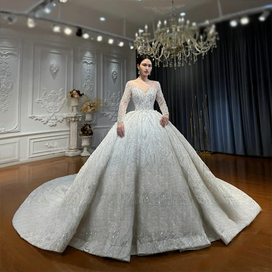 Full front view of a heavy beaded lace wedding gown with a voluminous ball gown skirt and shimmering silver embroidery for a royal bridal look.