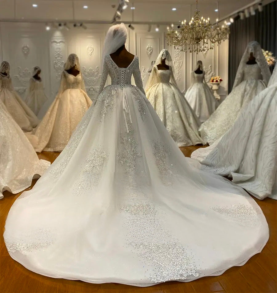 Wide-angle back view of an off-white wedding dress on a mannequin, emphasizing the grand sweep of the beaded cathedral train and the uniform sparkle of the pearl-encrusted fabric.