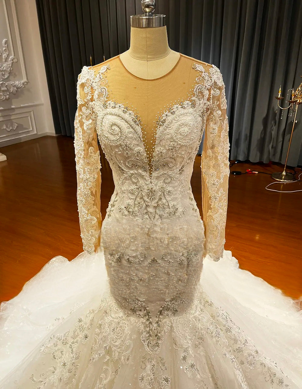 Detailed shot of the high-quality beaded bodice on a mermaid wedding dress, featuring an illusion plunging neckline and sheer lace long sleeves.