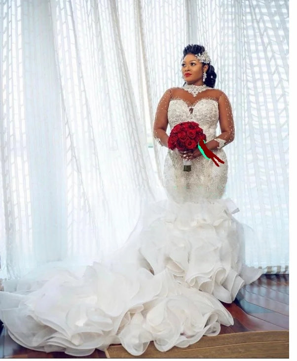 Elegant bridal portrait showcasing a ruffled mermaid wedding dress for African brides, highlighting the intricate silver crystal beadwork on the bodice and a voluminous layered train.