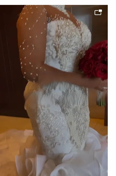 Close-up detail of a high-neck beaded bridal gown, showcasing the sophisticated silver lace embroidery, hand-sewn crystal embellishments, and sheer sleeves with scattered pearls.