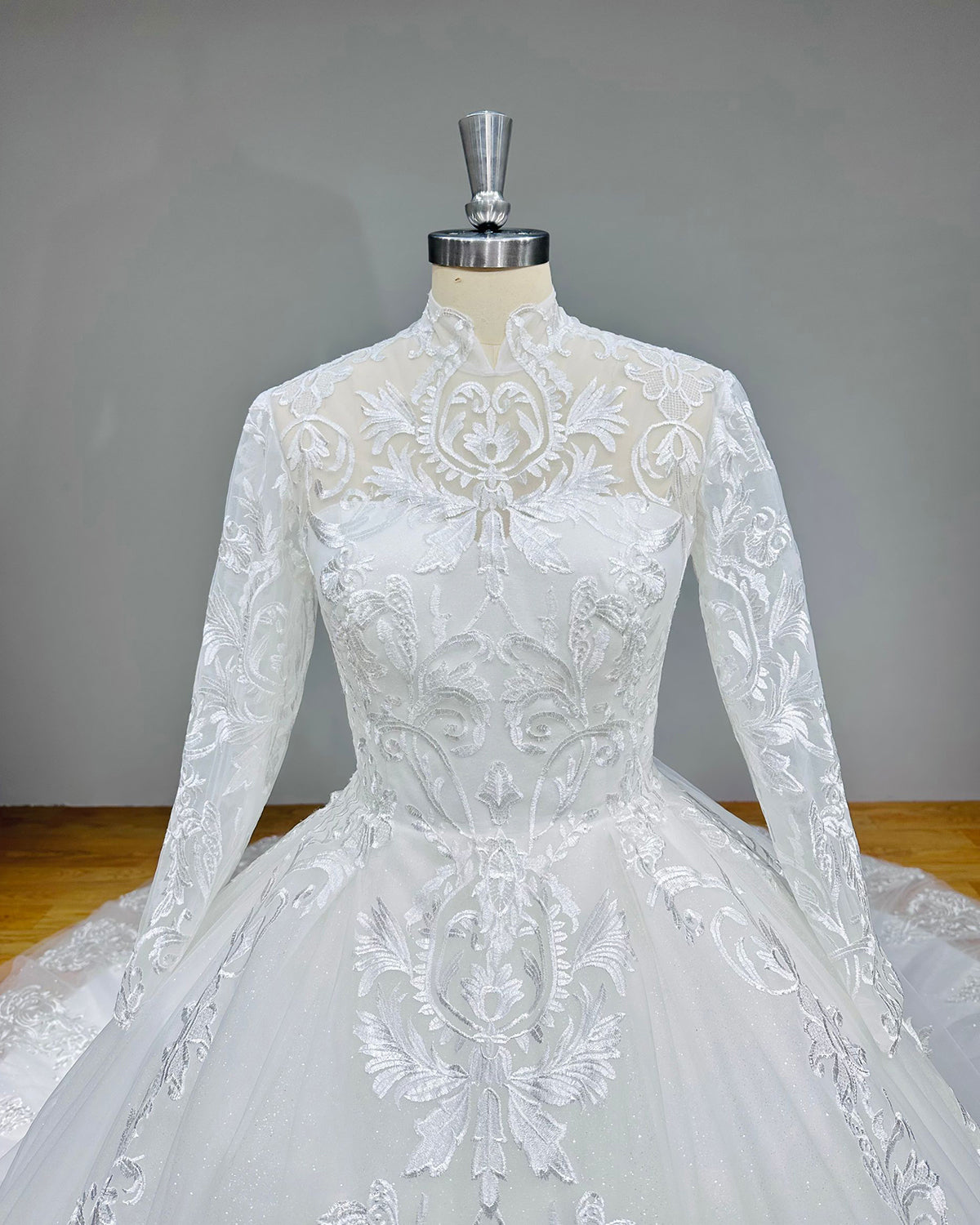 Detailed front view of a mock high collar bridal bodice emphasizing the textured lace applique placement and sheer illusion neckline.