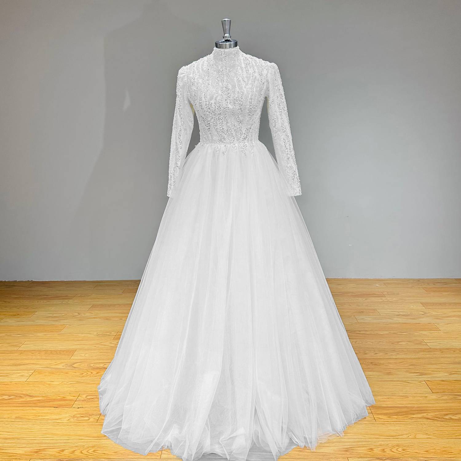 Classic modest long-sleeve wedding dress featuring a high collar, glistening sequin embroidery, and a voluminous layered tulle skirt.