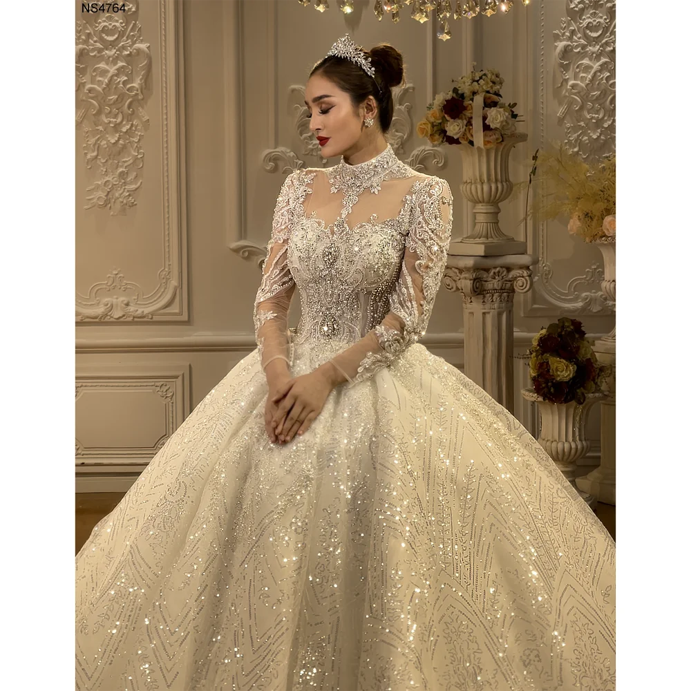 Close-up front view of a luxury wedding dress featuring a high neckline and intricate lace embroidery with shimmering crystal and rhinestone detailing.