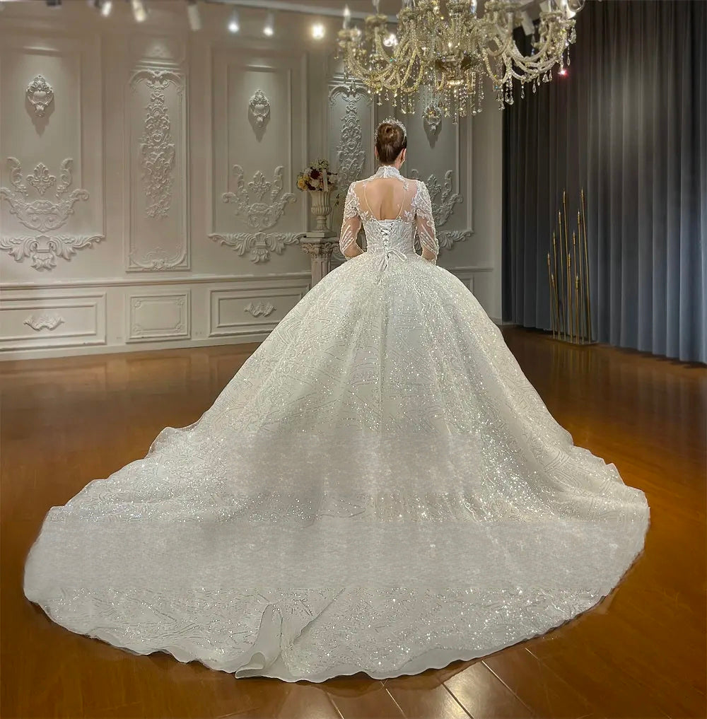 Stunning back view of a lace ball gown wedding dress showcasing an elegant lace-up corset back and a magnificent shimmering cathedral-length train.