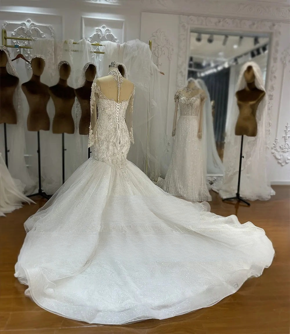 Full back view of an elegant mermaid wedding dress, emphasizing the sweeping sheer tulle train with shimmering details and the intricate corset closure.
