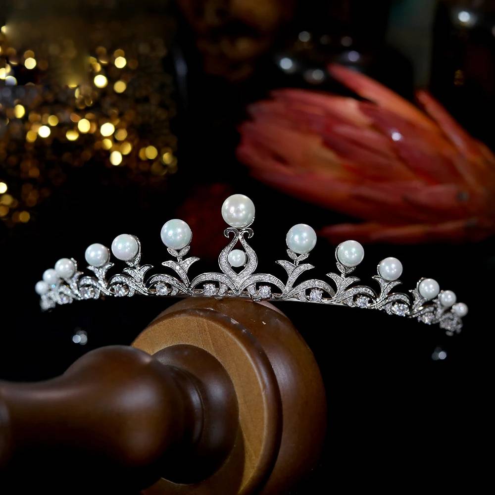 Premium presentation of a high-quality pearl crown CZ tiara for brides, showcased on a polished wooden stand with celebratory background bokeh.